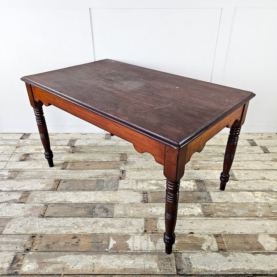 an Early 20th Century ecclesiastical-style pitch pine table with slim legs and a shaped apron. Ideal for dining rooms, living rooms, or studies, this antique pine table adds tasteful charm to any space, blending seamlessly with various décor styles for a warm and character-filled home.