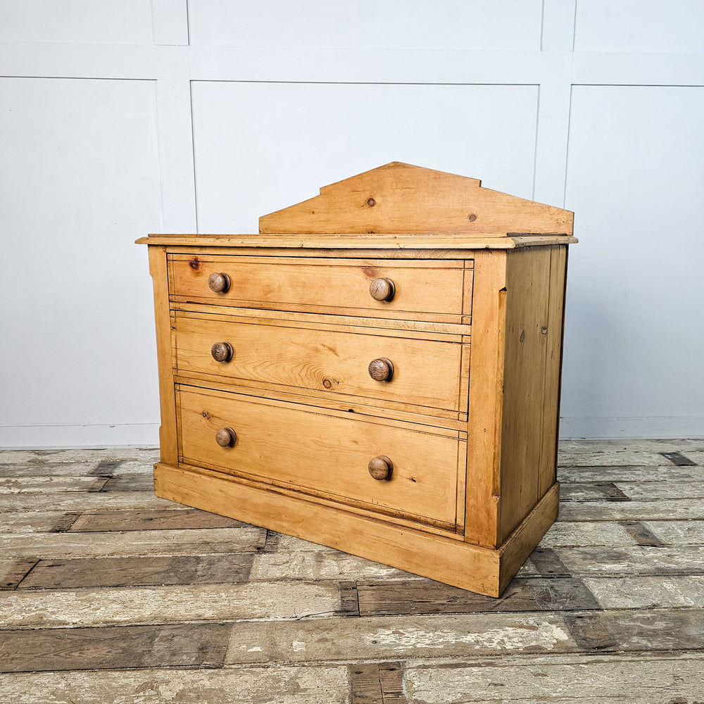 Three-quarter perspective of the pine chest of drawers, with focus on the distinctive Aesthetic Movement design and wooden knobs.