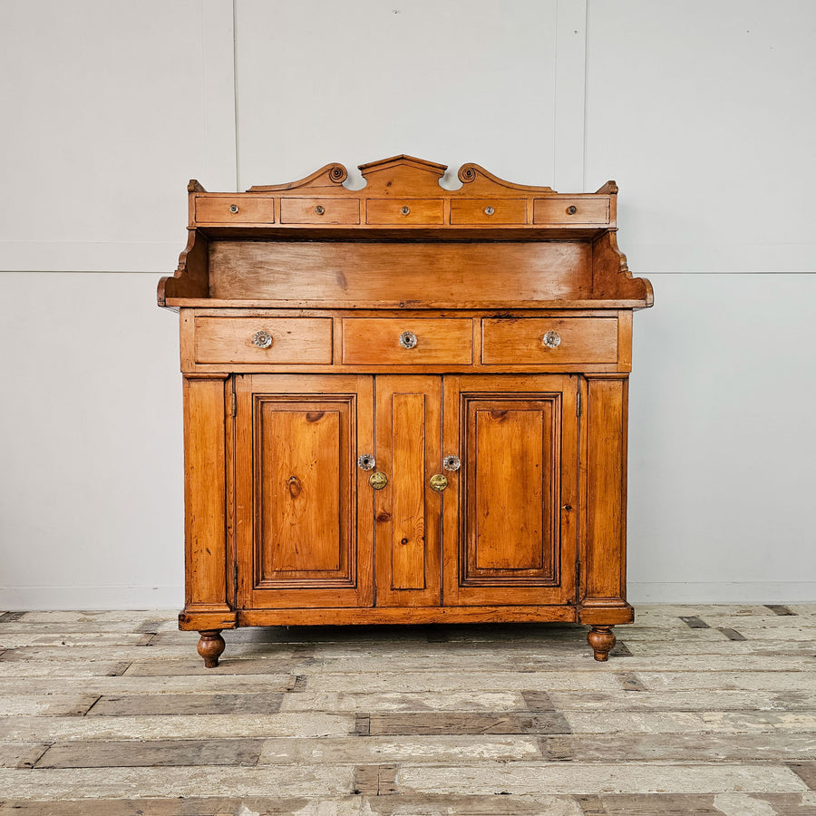Front View: Scottish Pine Dresser featuring a shaped gallery back with a series of small drawers above a further three drawers and two door cupboard. 