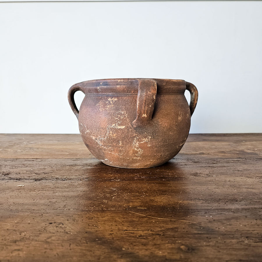 Close-up view of a rustic Turkish earthenware pot with rounded shape and small handles, perfect for adding traditional charm to any space.