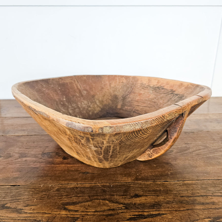 Rustic antique dough bowl with metal repairs and carved handle