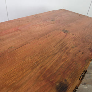 A rustic antique pine chest of drawers featuring a two-over-two drawer layout with Art Nouveau–influenced brass handles. The pine is finished in a warm red stain with a waxed surface that highlights the grain. The piece stands on a solid plinth base with simple moulded detail.