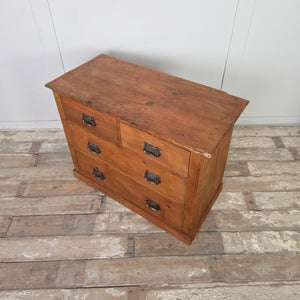 A country-style antique pine chest with a warm red-stained wax finish. It includes two short drawers above two long drawers, all fitted with curved brass handles showing Art Nouveau influence. The chest is set on a plain plinth.