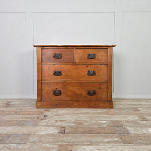 A country-style antique pine chest with a warm red-stained wax finish. It includes two short drawers above two long drawers, all fitted with curved brass handles showing Art Nouveau influence. The chest is set on a plain plinth.