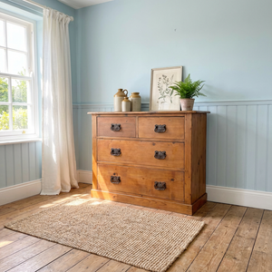 A rustic farmhouse-style antique pine chest of drawers from the late 19th to early 20th century, featuring a two-over-two arrangement and decorative Art Nouveau–influenced brass handles. The pine has a warm red-stained finish sealed with wax, and the chest is set on a solid plinth base.