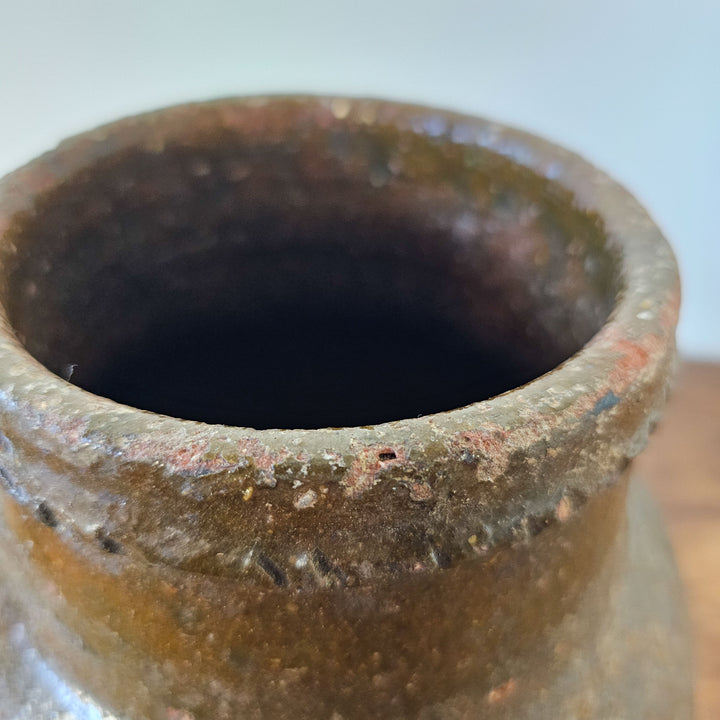 A close up of the opening of an antique terracotta olive pot