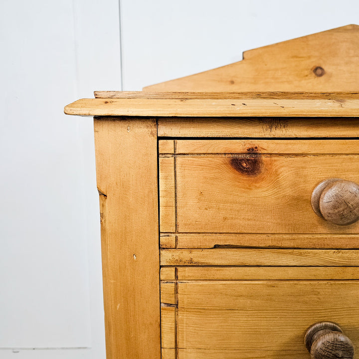 Close-up of the top corner of a 19th-century Aesthetic Movement pine chest, highlighting the wood's natural grain and angular back detail.