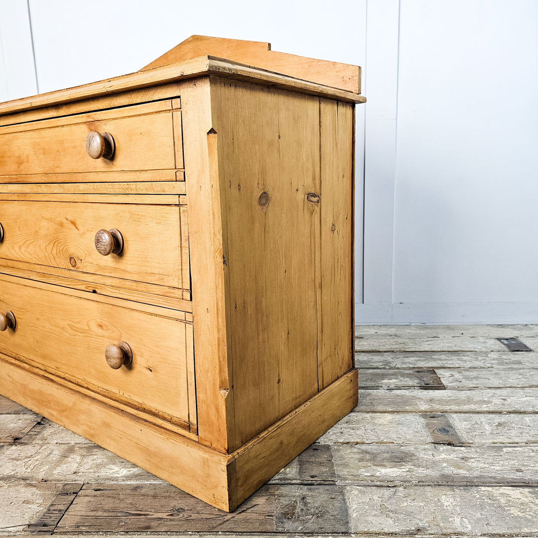 Side view of the antique pine chest, emphasizing the depth and solid construction of the drawer sections and side panel.