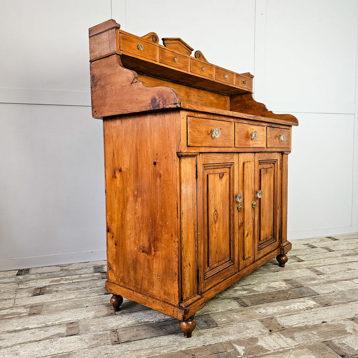 Angled View: Scottish Pine Dresser featuring a shaped gallery back with a series of small drawers above a further three drawers and two door cupboard. 