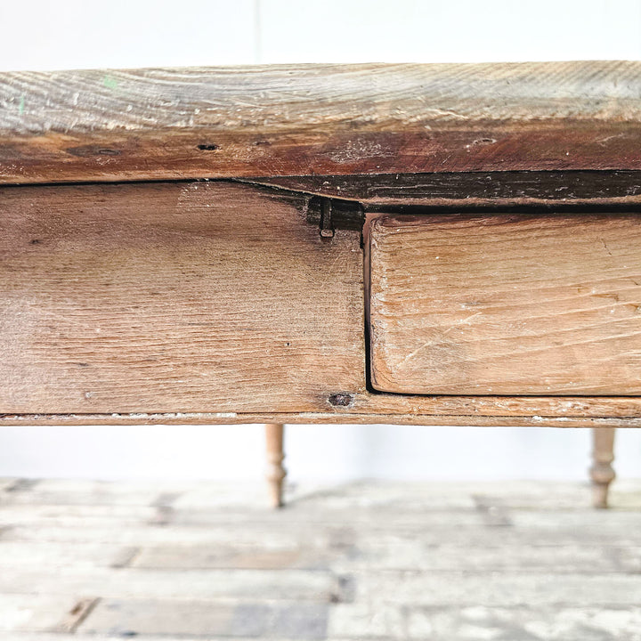 A close up of some historic damage to the drawer on an antique pine table