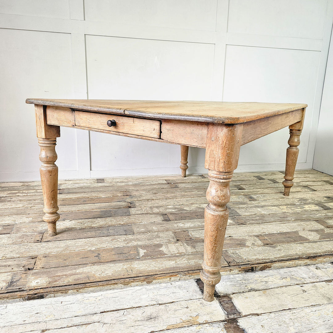 Front angles view, showing drawer at one end of a rustic pine dining table