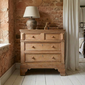 An early 19th-century pine and ash chest of drawers in a two-over-two layout with round wooden knobs and original ivory escutcheons. A simple farmhouse style piece with panelled sides and shaped bracket feet, providing useful storage around the home.