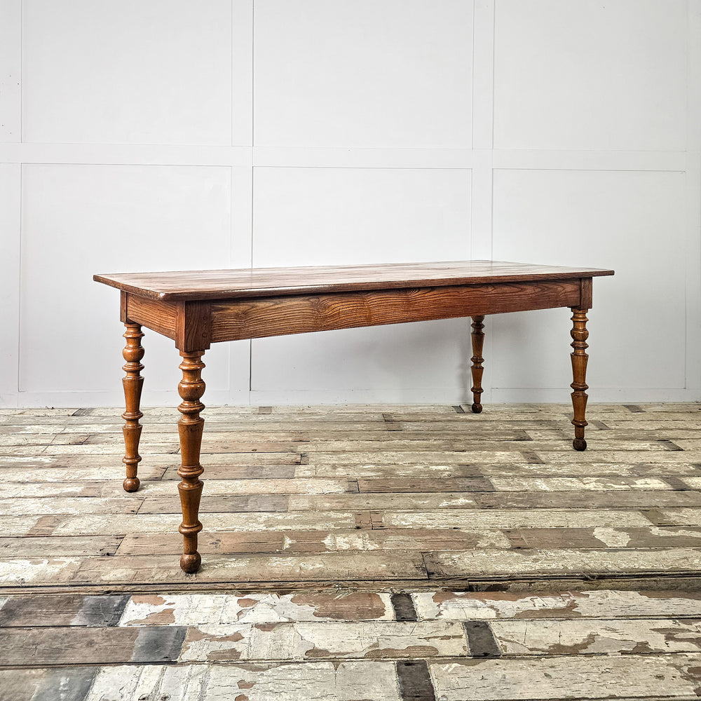 Large antique French dining table in elm and fruitwood with planked top and turned leg base
