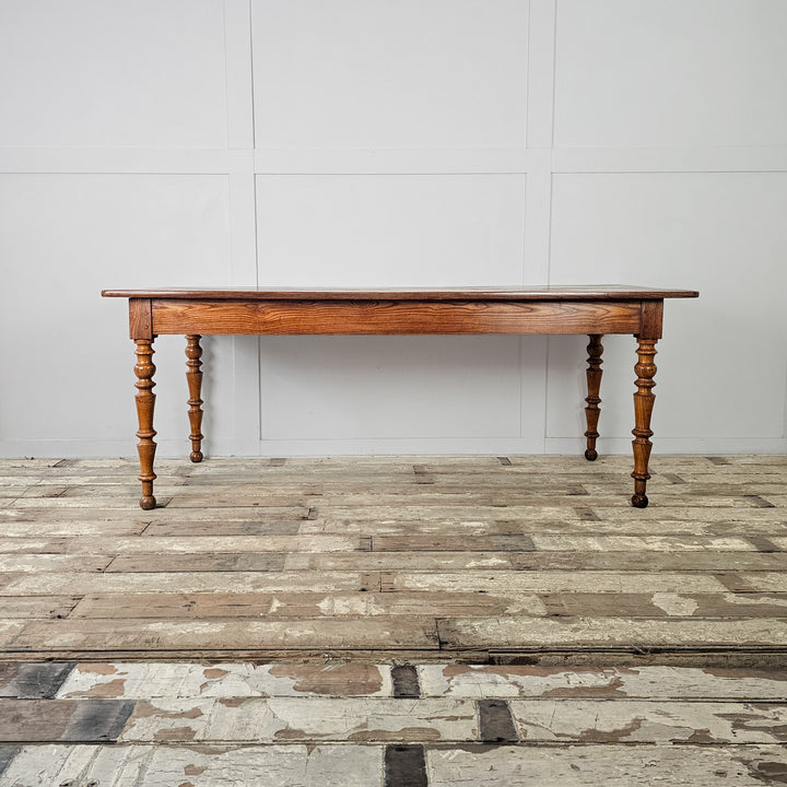 Elm and fruitwood antique table with turned legs and a smooth planked top for dining or prep
