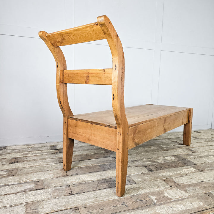 Antique French bench in rustic pine with curved backrest.
