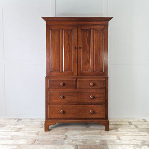 Early 20th century oak Linen Press with a simple cornice, symmetrical two part layout, internal shelving above and two over two drawers below with turned wooden knobs.