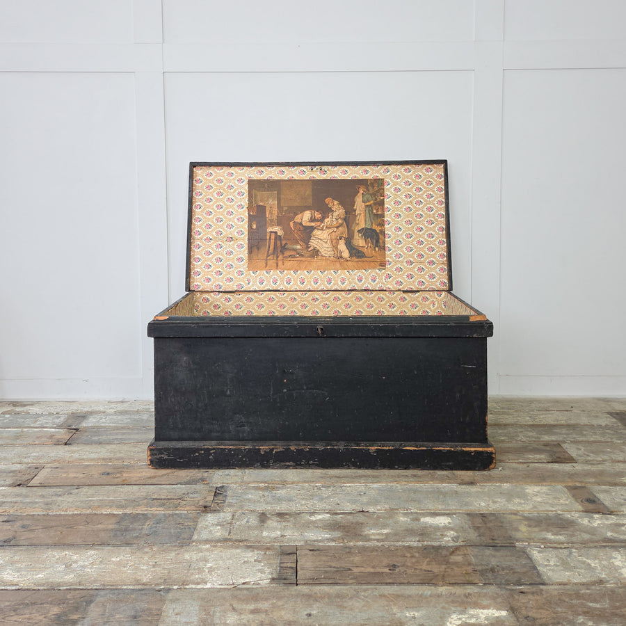 A Victorian painted pine chest with original black finish and metal side handles for easy storage use.

