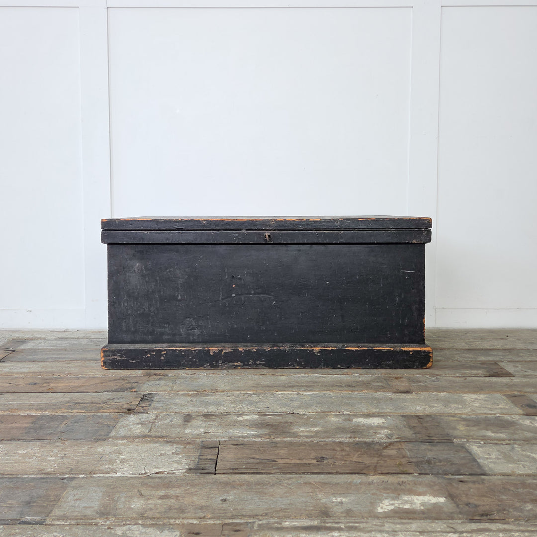 A painted antique pine trunk with internal lining, used for versatile storage throughout the home.
