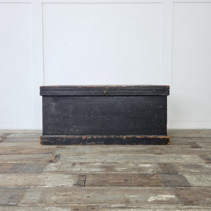 A painted antique pine trunk with internal lining, used for versatile storage throughout the home.
