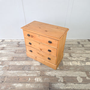 Early 20th century antique pine chest with three functional drawers, each fitted with metal swing handles, raised on a plinth base and finished in honey pine tones, suitable for use as farmhouse bedroom drawers, a rustic cottage storage chest, or traditional country house furniture.