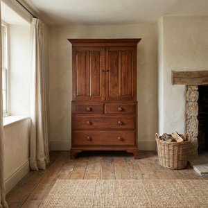 Antique English oak Housekeepers Cupboard from the early 20th century with two panelled doors opening to internal shelving and a two over two drawer base on bracket feet.