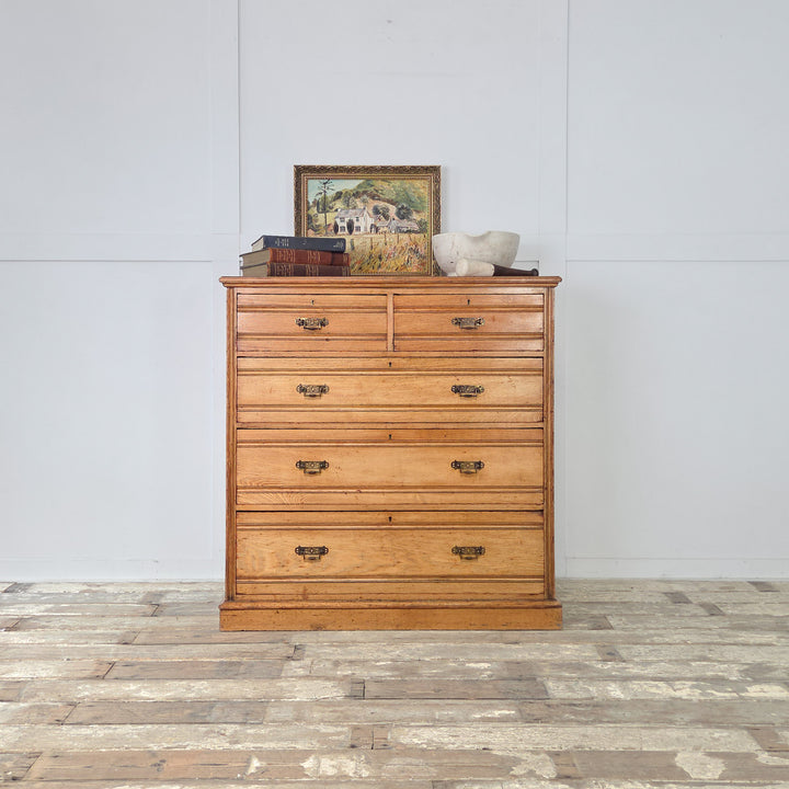 Late-Victorian ash chest of drawers with two short over three graduated long drawers, reeded fronts, original brass drop handles and a warm golden patina.