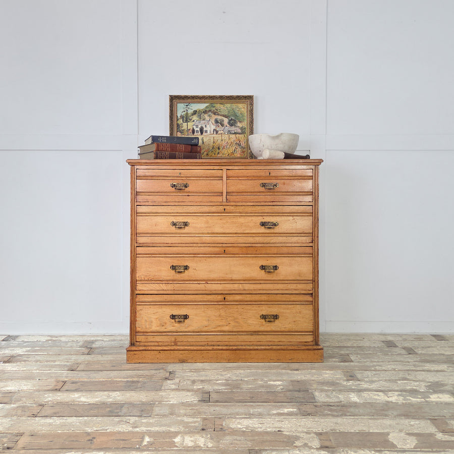 Late-Victorian ash chest of drawers with two short over three graduated long drawers, reeded fronts, original brass drop handles and a warm golden patina.