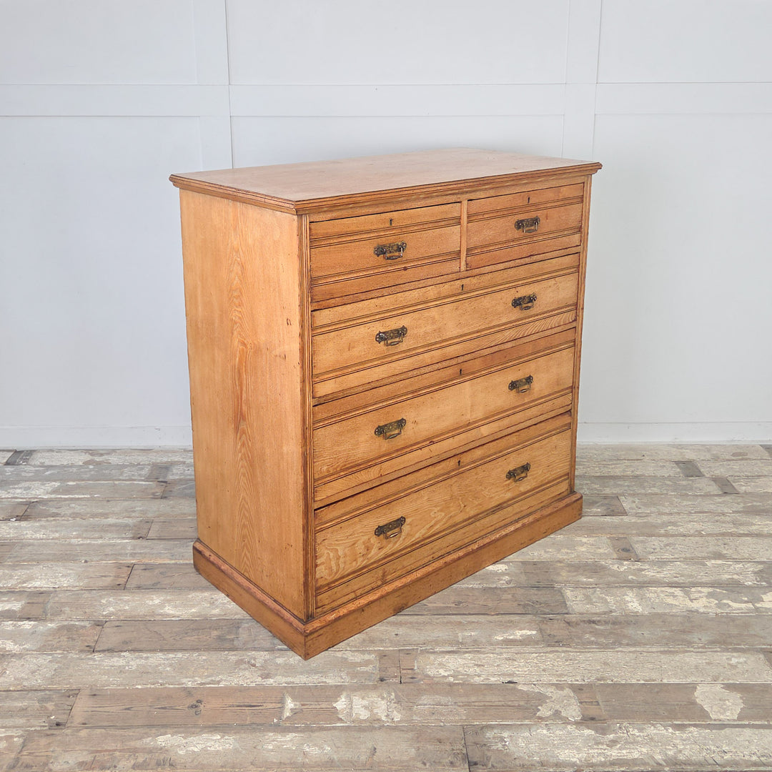Well-proportioned antique ash chest with two short over three graduated drawers, reeded fronts, brass drop handles, and a rich golden finish.