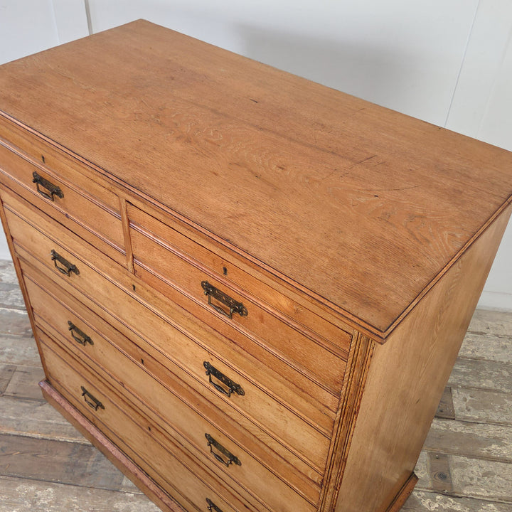 Victorian ash chest of drawers with a golden patina, reeded drawer fronts, brass drop handles, and two short drawers over three long graduated drawers.