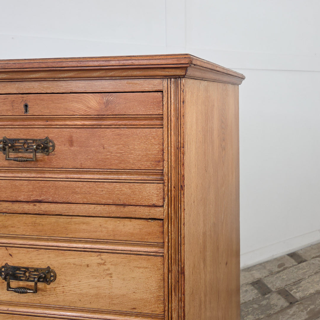 Antique bedroom storage chest in ash, late-Victorian, with five drawers, reeded detailing, original brass drop handles, and an enclosed plinth base.