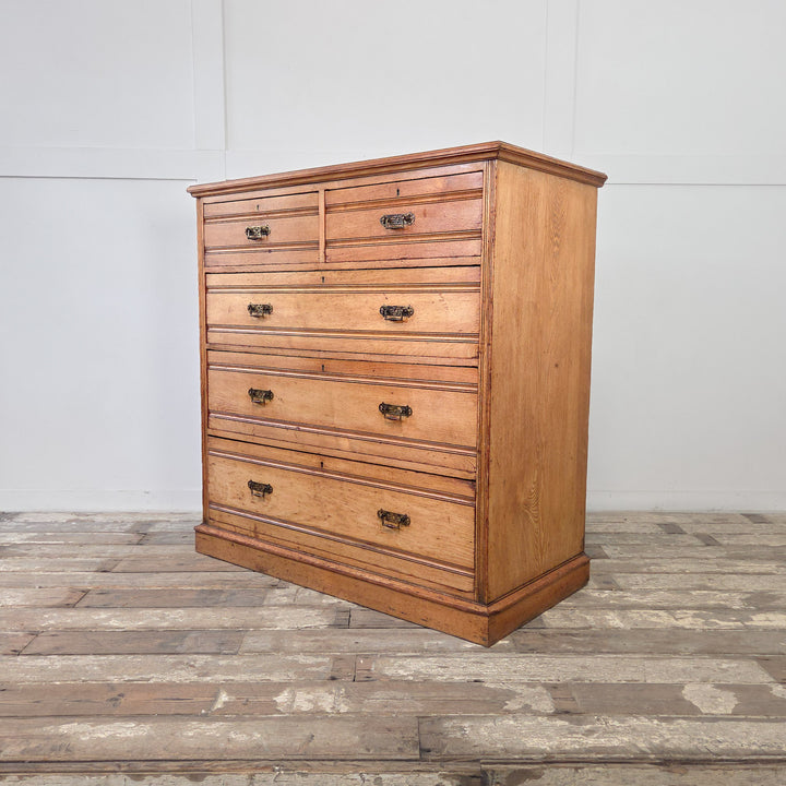 19th century ash chest with reeded fronts, two short over three graduated drawers, original brass drop handles, and a solid plinth base.