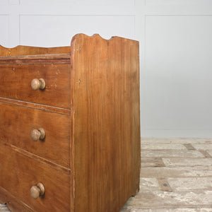 Early 20th century ash chest of drawers with three graduated drawers, a gallery-style back to the rear edge of the top, and a shaped plinth base.
