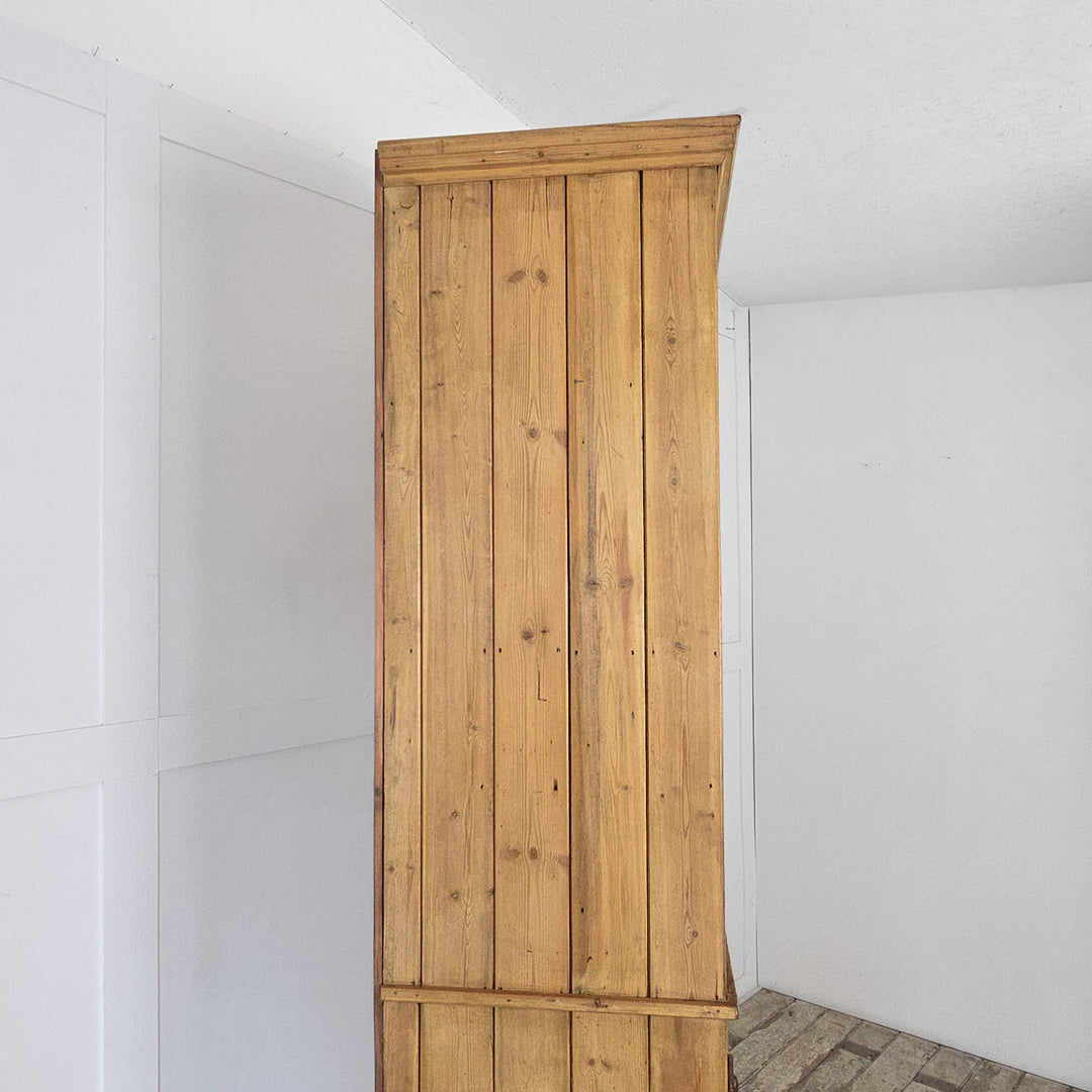 A tall antique pine bank of drawers from the early 20th century featuring thirty-four drawers above a lower cupboard with panelled doors and two internal shelves, all finished with a clear wax seal.