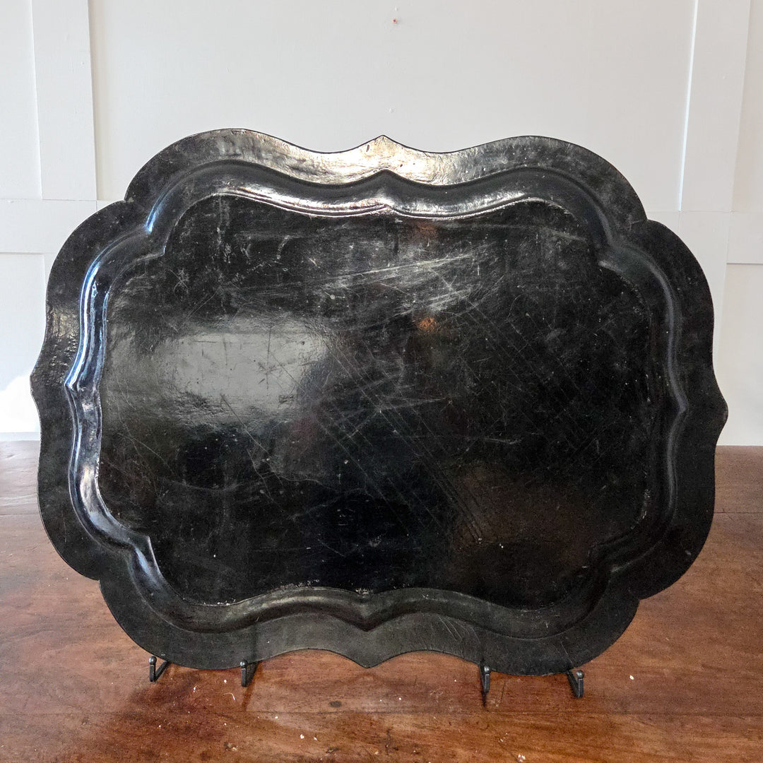 A large Victorian papier-mâché serving tray from the 19th century with a lacquered black background, hand-painted floral decoration, mother-of-pearl inlay and scalloped edge, ideal for use as a dining room centrepiece or as a decorative wall tray.