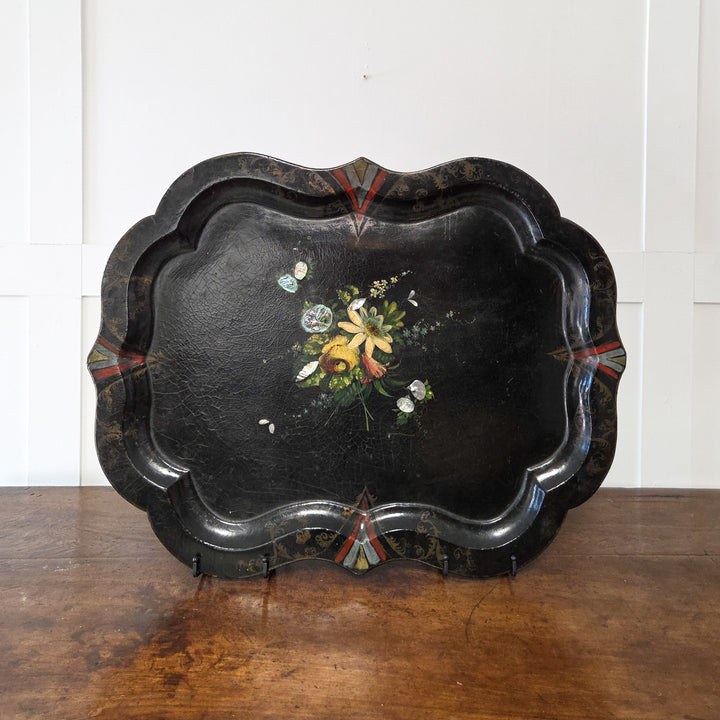 A large Victorian papier-mâché serving tray from the 19th century with a lacquered black background, hand-painted floral decoration, mother-of-pearl inlay and scalloped edge, perfect as a decorative centrepiece, wall-mounted tray or console display.
