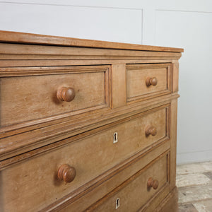 A farmhouse style early 19th-century chest of drawers combining pine and ash, with panelled sides and shaped bracket feet. The two-over-two drawers are fitted with round knobs and original ivory escutcheons for practical everyday use.