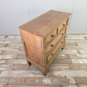 A cottage style early 19th-century storage chest in pine and ash with a two-over-two layout, round knobs and original ivory escutcheons. Decorative bracket-style feet lift the piece and panelled sides add quiet detailing.