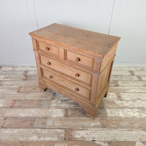 A country house style pine and ash bedroom chest from the early 1800s with a two-over-two layout, panelled sides and shaped bracket-style feet. Original ivory escutcheons and round knobs complete this practical storage chest.