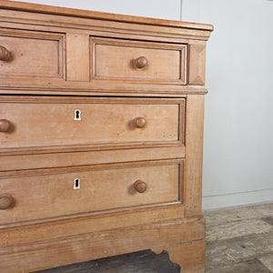 A practical early 19th-century storage chest in rustic pine and ash with a two-over-two arrangement and round wooden knobs. The original ivory escutcheons, panelled sides and shaped bracket feet give the piece a simple farmhouse style look.