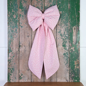 A handmade cottage-style bow created from limited vintage Laura Ashley “Firenze” fabric featuring a pink damask pattern. Fully padded for sculpted shape with long tails and a brass hoop. A versatile decorative hanging bow for doors, furniture or wedding keepsakes.