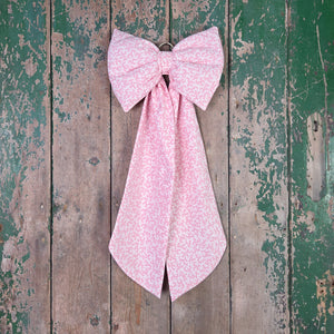 A large handmade bow sewn from vintage Laura Ashley “Firenze” cotton with a pale pink scrolling damask print. Padded for structure and fitted with an antiqued brass hanging hoop, offering a farmhouse or country decorative bow ideal for doors and home décor.