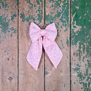 A handmade decorative bow crafted from rare vintage Laura Ashley “Firenze” damask-print cotton in soft pink. Featuring padded shaping, tapered tails and a brass hoop. A cottage-style hanging bow suitable for doors, bannisters or thoughtful gifting.