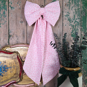 A handmade decorative bow crafted from vintage Laura Ashley 1985 “Firenze” cotton with a scrolling pink damask print. Padded for fullness and shaped with long tails, complete with a brass hanging hoop. A cottage-style fabric bow suited to doors, furniture and keepsake décor.