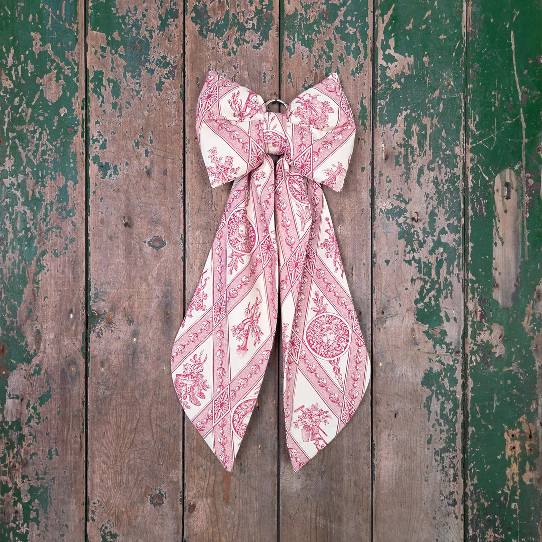 Country House Bow made by hand in Shropshire using carefully sourced vintage fabric. The structured, padded body and tapered tails create a full, decorative shape, complemented by a brass hanging hoop. A limited-edition handmade bow for doors, mantels, or festive displays.