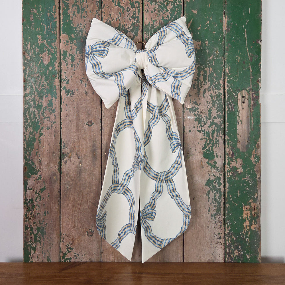 A decorative fabric bow handmade from vintage Sanderson Carousel fabric with padded shaping, long tapered tails and an antiqued brass hoop for hanging. Each bow is created in limited batches using genuine vintage fabric, giving it a classic cottage and farmhouse character.
