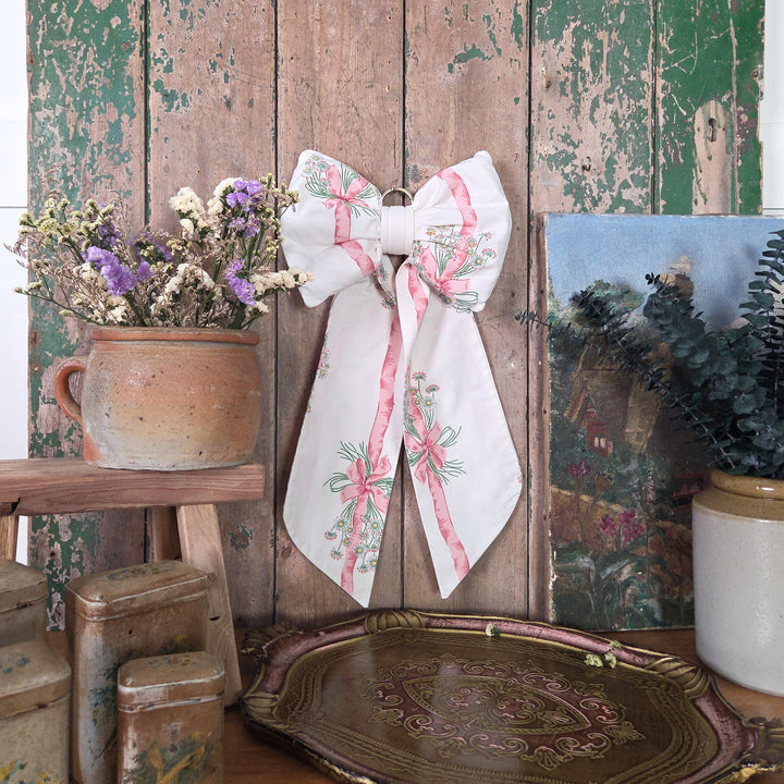 A large handmade bow from the Country House collection, crafted from vintage 1986 Sanderson “Daisy Stripe” fabric. Structured and lightly padded with long tapering tails and a brass hanging hoop, a farmhouse style fabric bow made in small batches.