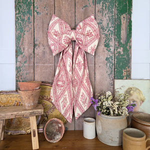 Handmade decorative fabric bow created in limited quantities from sourced vintage fabrics. With a softly padded shape, tapering tails, and antiqued brass hoop, it’s a versatile accessory for adding country-house charm to home décor.