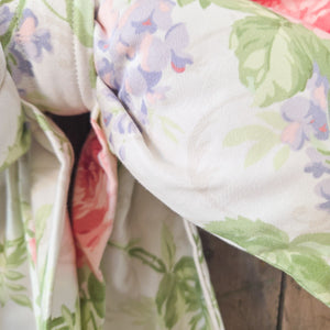 A handmade Country House Bow featuring vintage Sanderson Roses & Lilacs fabric, designed with a padded body and long tapering tails. Finished with an antiqued brass ring, this limited edition bow is restricted to just three examples, ideal for rustic interiors.