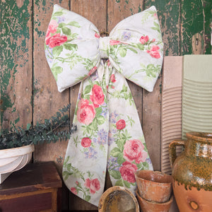 A unique handmade Country House Bow created in vintage Sanderson Roses & Lilacs fabric, displaying classic English florals in soft pastel shades. Each bow is padded, shaped with long tails, and finished with a brass hanging ring, limited to three pieces.