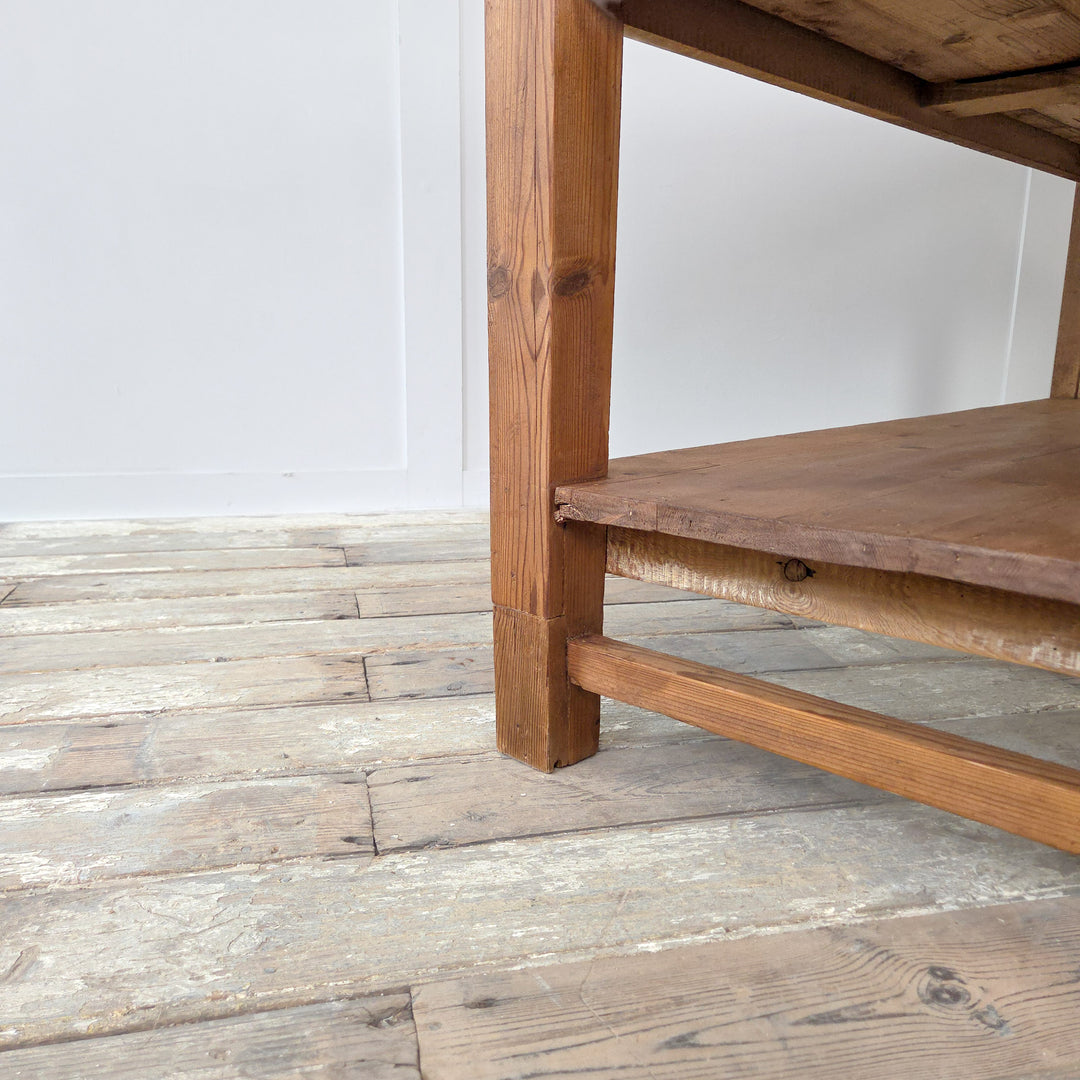 An antique 19th century Victorian pine farmhouse table with rustic planked top, twin storage drawers and a shaped lower shelf. Supported on sturdy straight legs, this versatile piece functions as a kitchen prep table, a serving table, or a hallway console. Its authentic Victorian design makes it an ideal antique pine sideboard or work table, combining practical surface space with useful storage for modern interiors.